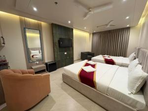 a hotel room with two beds and a chair at Eve Hotel in Varanasi