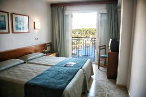 
a hotel room with a bed and a window at Hotel Villa Sirena in Cala Figuera
