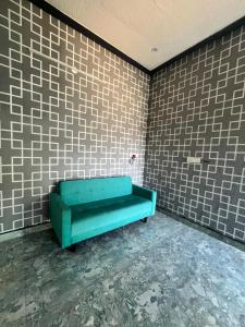a green couch in a room with brick walls at Chamundi Temple-Hill View in Mysore