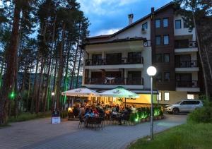 people sitting under umbrellas outside of a building at Апартамент Боров рай in Velingrad