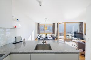 a kitchen with a sink and a living room at Chasa AlpVista in Sent