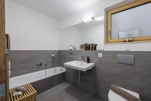 a bathroom with a sink and a toilet and a tub at Chasa AlpVista in Sent +9 photos