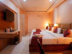 a hotel room with a bed and a desk and a television at Hotel Nirvvana Residency in Varanasi +47 photos