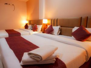 two beds in a hotel room with towels on them at Hotel Nirvvana Residency in Varanasi
