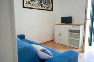a living room with a blue couch and a television at Villette Calliope in Torre Specchia Ruggeri