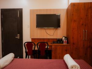 a bedroom with a tv and a table and chairs at Hotel Nirvvana Residency in Varanasi