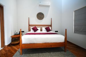 a bedroom with a bed with white sheets and red pillows at The Villa - Premium Private Pool Villa in Vaduvanchal +29 photos