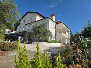 a white house with a car parked in front of it at Apartment für 4 Personen mit Jacuzzi und Pool in Lovran