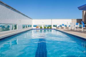 Una piscina con sillas azules en un edificio. en Flat Macaé, en Macaé