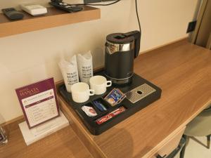 a coffee maker and cups on a table at Hotel Hanata Kochi in Cochin