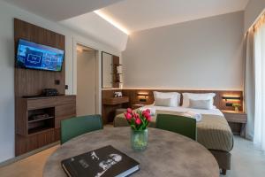 ein Hotelzimmer mit einem Bett und einem Tisch mit Blumen in der Unterkunft CENTRO Suites in Kalamata