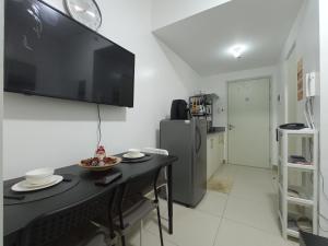 a kitchen with a table with a television on the wall at SFC Cool Suites by SMDC Tagaytay in Tagaytay