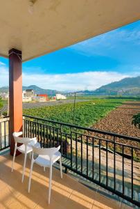a balcony with two chairs and a view of a field at Homestay Gavilla Dieng in Diyeng