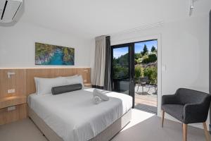 a bedroom with a bed and a chair and a window at Luna Lodge Wānaka - digital check-in only in Wanaka