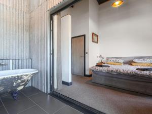 a bathroom with a tub and a bed and a mirror at Rusty Barn in Gloucester