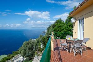 a balcony with a table and chairs overlooking the ocean at VivimiHome - Casa Tiberio in Conca dei Marini