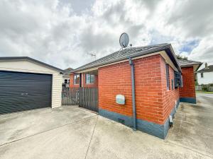 a red brick building with a gate and a garage at Sweet Home in Avalon in Lower Hutt