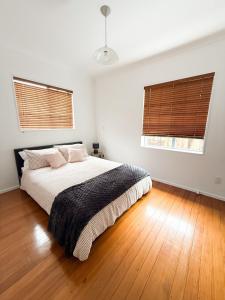 a bedroom with a large bed and two windows at Sweet Home in Avalon in Lower Hutt