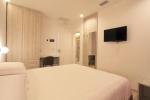 a white bedroom with a bed and a tv on the wall at Residenza del Centro in Fabriano