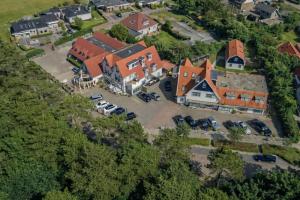 an aerial view of a large house with a parking lot at Hotel het Uilenbos in De Koog