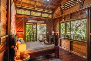a bedroom with a bed in a wooden room with windows at Charming Villa Surrounded by Nature Punta Uva in Puerto Viejo