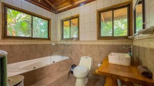a bathroom with a tub and a toilet and a sink at Charming Villa Surrounded by Nature Punta Uva in Puerto Viejo