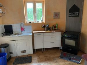 a kitchen with white cabinets and a sink and a stove at A l'abri des flots in Ambleteuse