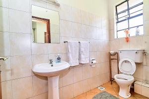 a bathroom with a sink and a toilet and a mirror at GoldKent Kileleshwa in Gatunga +2 photos