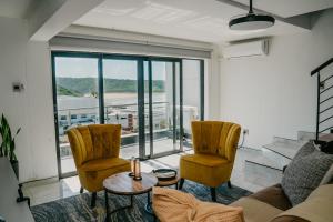 a living room with a couch and two chairs at Gonubie Beachside Delight Apartment in East London