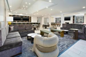 a living room with couches and tables and a bar at DoubleTree by Hilton Hotel Detroit Novi in Novi