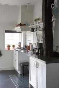a kitchen with white cabinets and a black counter top at De Reggestee in Hellendoorn +4 photos
