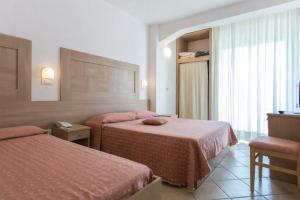 a hotel room with two beds and a window at Hotel Excelsior in Cattolica