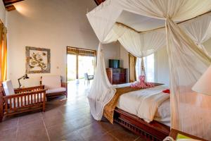 a bedroom with a canopy bed and a chair at Villa Taman di Blayu by AGATA in Tabanan