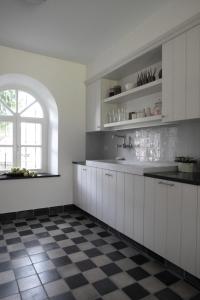 a kitchen with white cabinets and a checkered floor at De Pastory in Grote-Brogel