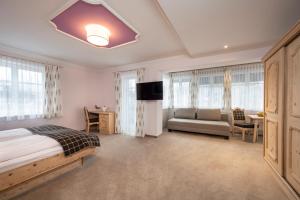 a bedroom with a bed and a couch and a television at Hotel Garni Carl Michael in Strobl