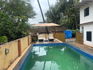 a pool with two chairs and an umbrella at SAHAY VILLA RESORT in Durbate
