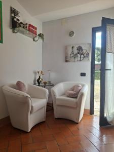 a living room with two white chairs and a table at Papaveri & Papere in Casetta +26 photos