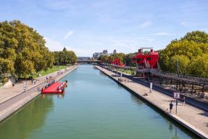 a river with a red boat in the middle at Art Hotel Paris Est in Pantin
