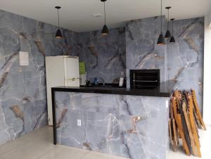 a kitchen with a counter with a marble wall at Casa linda buzios in Búzios