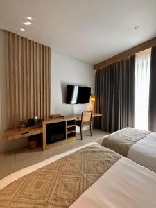 a hotel room with a bed and a television at Truntum Boutique Mandalika in Kuta Lombok