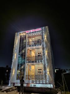 a man standing in front of a tall building with lights at Hotel Dayalu palace in Vrindāvan