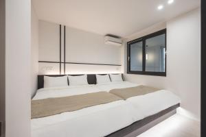 a white bedroom with a large bed with a window at GOYURe 고유리 in Seoul
