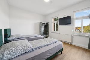 two beds in a room with a tv and a window at Apartment Alte Bäckerei in Zwenkau
