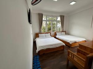 two beds in a room with a window at Spring Hotel in Da Lat