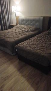 two beds in a bedroom with a wooden floor at D Elite in Kota Bharu