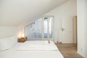 a white bedroom with a bed and a staircase at Wellnessoase mit Sauna und Garten in Würzburg