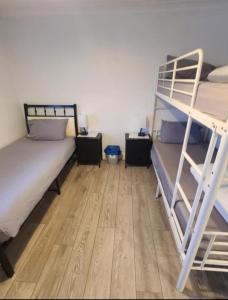 a bedroom with two bunk beds and a wooden floor at RoomZ-GATWICK-LONDON-Airport Parking-Travel Service in Ifield
