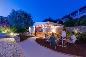 a group of people sitting at a table under a umbrella at Elite Corfu - Adults Friendly in Kommeno