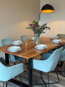 a wooden table with chairs and a vase of flowers at Moderne Wohnung mit Parkplatz und Kaffeevollautomat in Zülpich