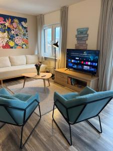 a living room with blue chairs and a television at Moderne Wohnung mit Parkplatz und Kaffeevollautomat in Zülpich
